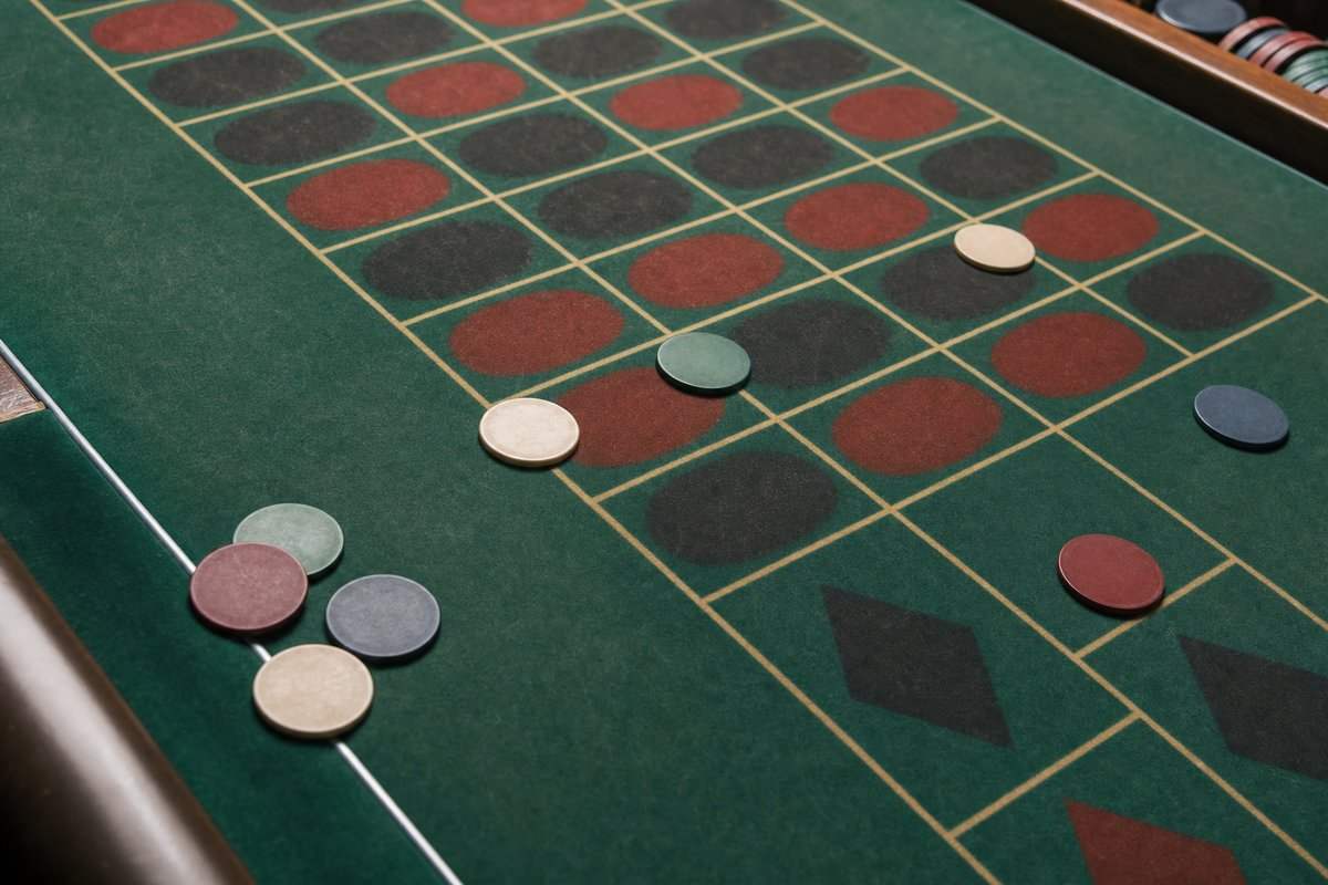 Ein abgenutztes Roulette-Tableau aus grünem Filz von oben, mit einzelnen Jetons